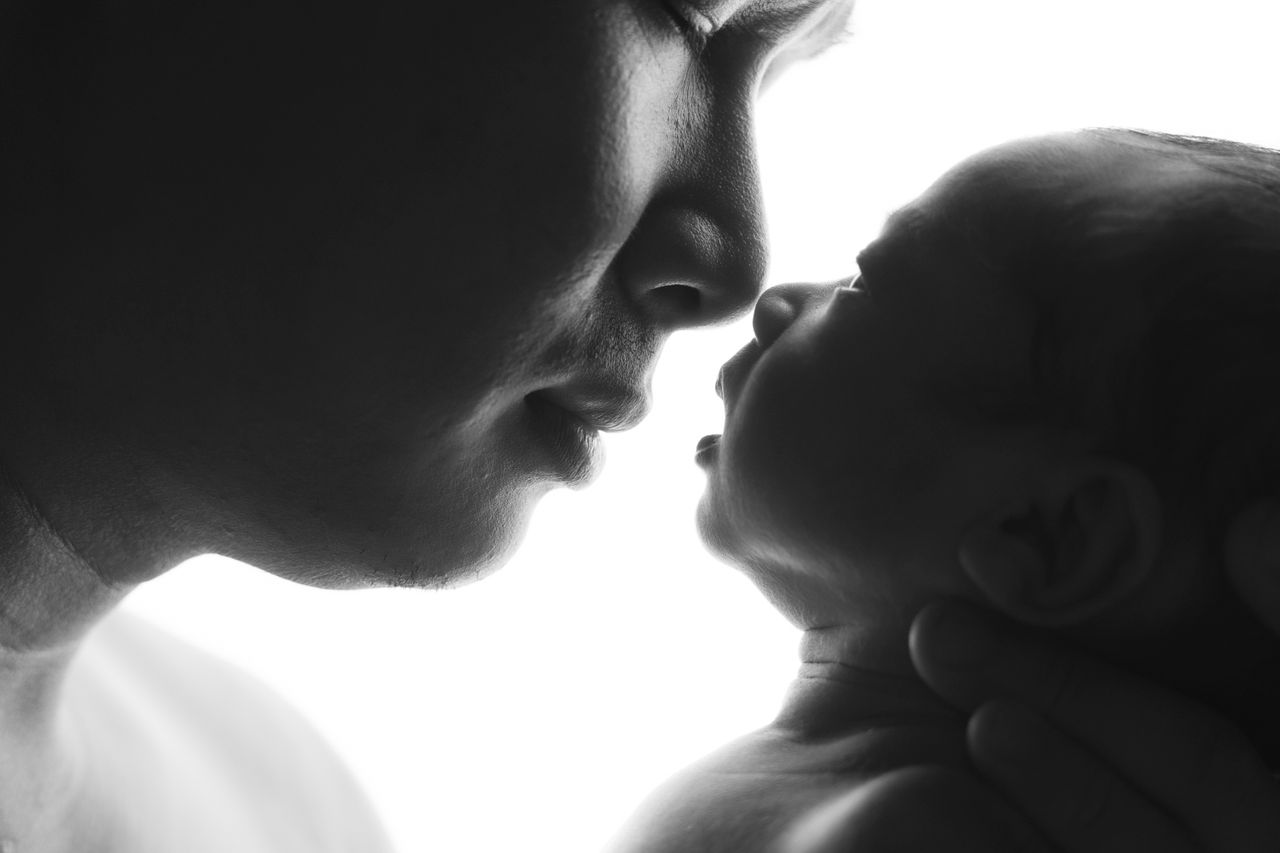 An intimate black and white portrait of a father bonding with his newborn, showcasing love and tenderness.