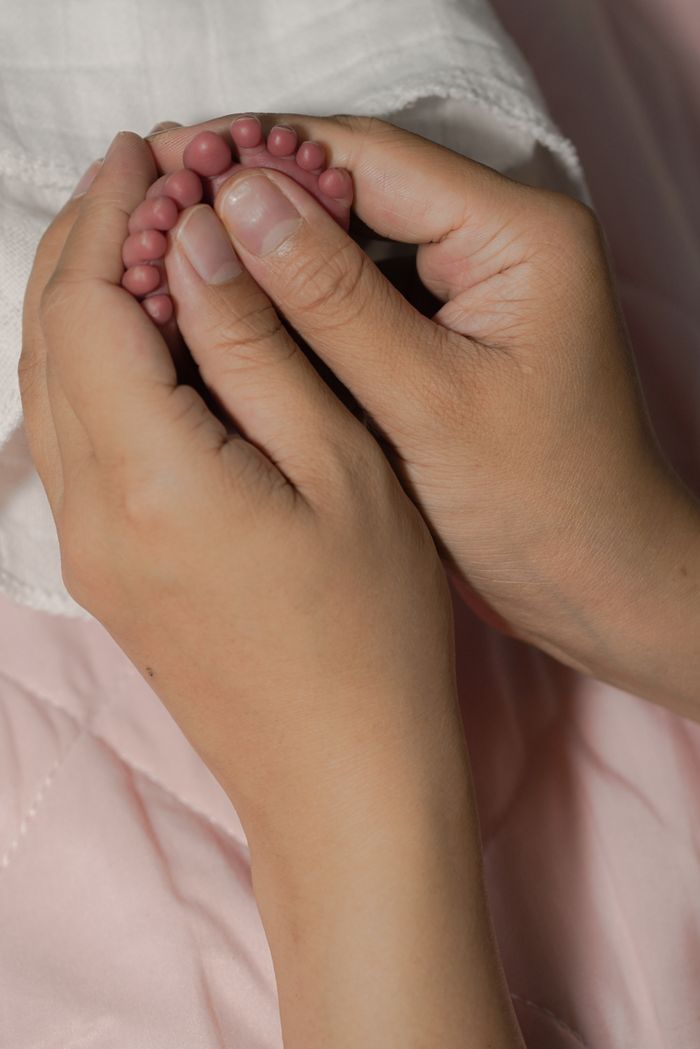 ours-journey Tender hands gently holding tiny baby feet, symbolizing love and care.