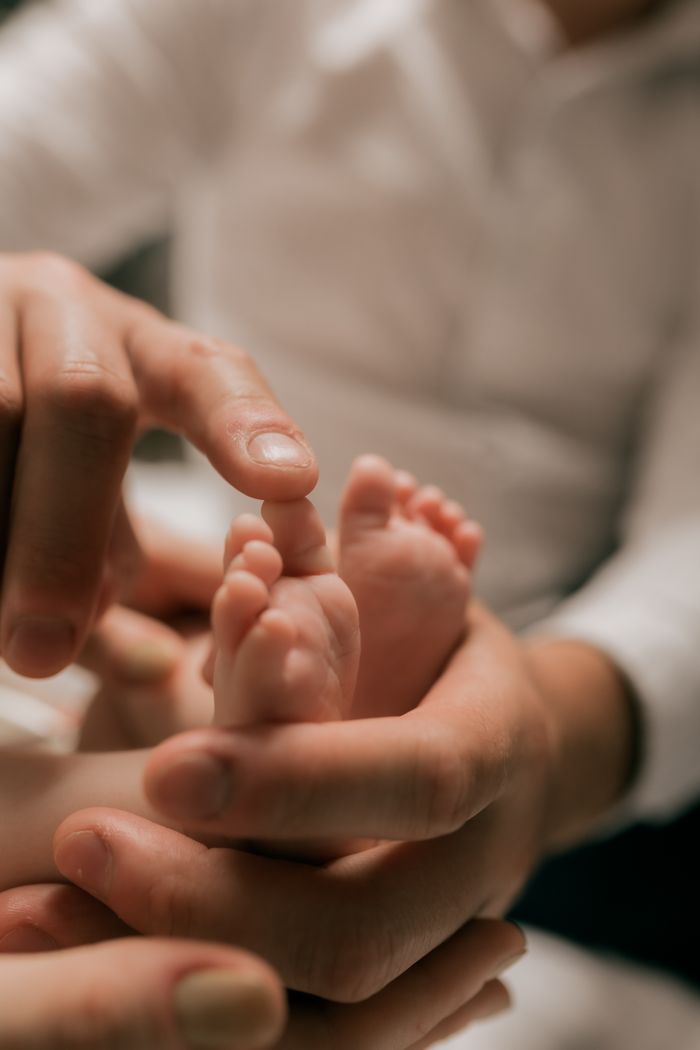 Close-up of an adult gently holding a baby's feet, symbolizing love and care.