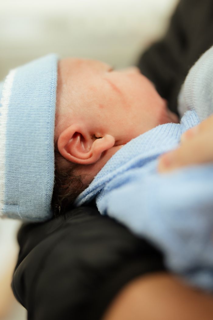 services-01 Close-up of a newborn baby wrapped in a soft blue blanket and wearing a blue beanie.